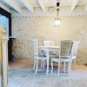 mesa de comedor blanca con sillas blancas y lámpara en La Fontenelle Chambres d'Hôtes, en Sainte-Sévère