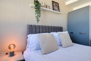 Una cama con almohadas blancas y una lámpara en una mesa. en Entire 1 bed apt in the centre of Stockport en Stockport