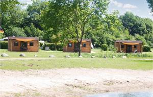 zwei Holzhütten auf einem Feld mit einem Baum in der Unterkunft Nice Home In Ssel With Lake View in Süsel