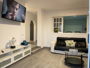 a living room with a couch and a tv on the wall at Adeje Deluxe Villas Santa Monica in Adeje