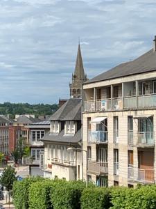 a building with a church steeple in the background at Au cœur de Lisieux 83 m2 et vue sur la Basilique in Lisieux