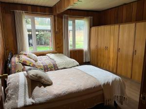 a bedroom with two beds and a window at Hostal Casa de Campo Rukaleufu a orillas del Rio Huiscapi in Villarrica