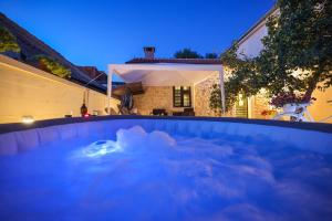 a hot tub in a backyard at night at Apartman Berto in Vrsi