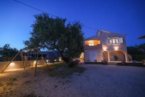 a house with a swing in front of a house at Apartman Berto in Vrsi