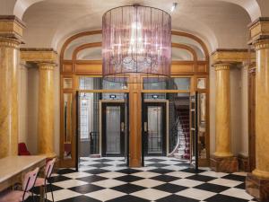 a lobby with a chandelier and a checkered floor at M Social Hotel Paris Opera in Paris