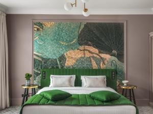 a bedroom with a green bed and a large painting on the wall at M Social Hotel Paris in Paris