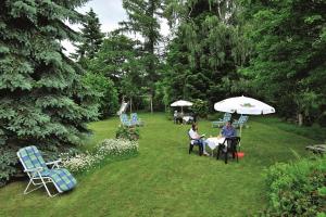 2 personnes assises à des tables dans une cour avec parasols dans l'établissement Hotel Pension Heidi, à Dobel