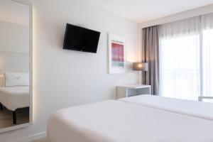 a white hotel room with a bed and a window at Helios Mallorca Hotel & Apartments in Can Pastilla