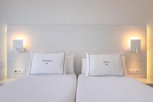 dwa białe łóżka w pokoju z dwoma światłami w obiekcie Helios Mallorca Hotel & Apartments w mieście Can Pastilla