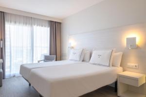 a hotel room with a large white bed and a window at Helios Mallorca Hotel & Apartments in Can Pastilla