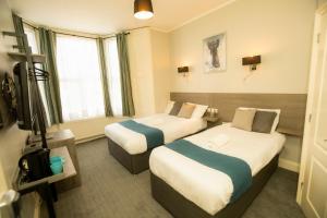 Una habitación de hotel con dos camas y un televisor. en Comfotel BLU, en Londres