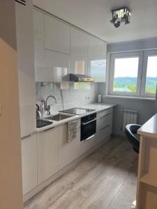 a kitchen with white cabinets and a sink and a window at Apartament Aspen in Polańczyk