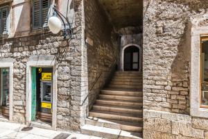 - un bâtiment en pierre avec des escaliers menant à une porte dans l'établissement House Poletti, à Šibenik