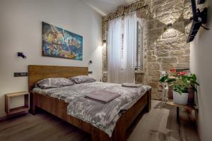 um quarto com uma cama e uma parede de pedra em House Poletti em Sibenik