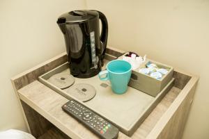a coffee maker and a cup and a remote control at Comfotel BLU in London