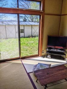 軽井沢町にあるOiwake House 1Bの大きな窓とテレビのあるリビングルーム