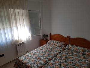a bedroom with a bed with a floral bedspread and a window at residencial nerea in Peñíscola