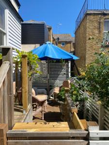 eine Terrasse mit einem blauen Sonnenschirm, einem Tisch und Stühlen in der Unterkunft 28 King Street in Margate