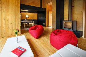 a living room with red chairs and a fireplace at La Marmote Albergo Diffuso di Paluzza Faas in Paluzza