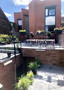 eine Terrasse mit Tischen, Stühlen und Topfpflanzen in der Unterkunft Loft atypique 192m2, terrasse, aux portes de Lille in Roubaix