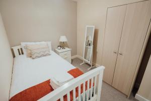 a small bedroom with a white bed and a mirror at Bellengers Apartments in Kidlington