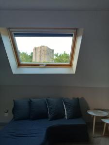 una ventana sobre un sofá azul en una habitación en Gîte 14 personnes à proximité du Puy du Fou "Bonheur à l' Aubépin" à 18 minutes du célèbre parc, en Pouzauges