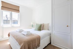 a white bedroom with a bed with towels on it at Spacious 3 bedroom flat with terrace in London