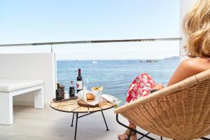 a woman sitting at a table with a bottle of wine at Sud Ibiza Suites in Ibiza Town