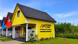 a yellow house with a black roof at Kolorowe Domki in Gąski