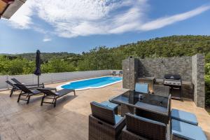 a patio with chairs and a swimming pool at Villa Arbareto with heated swimming pool in Srinjine