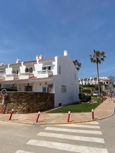 a large white building with a palm tree next to a street at Aldea beach, manilva in Castillo de Sabinillas