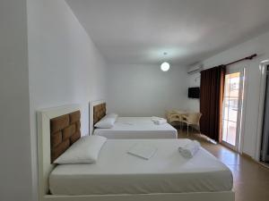 a room with two beds and a table and a window at Vila Geri in Ksamil