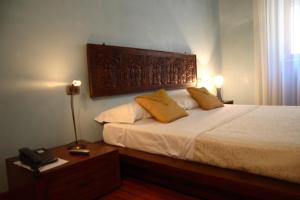 una camera da letto con un letto con lenzuola bianche e cuscini gialli di Casa Dei Mercanti Town House a Lecce