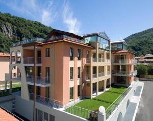an image of a building with a hill in the background at Golfo Gabella Lake Resort in Maccagno Superiore