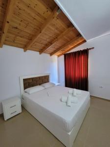 a bedroom with a large white bed with a red curtain at Vila Geri in Ksamil