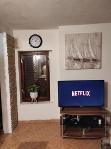 TV en una mesa en una habitación con reloj en Apartment Maja, en Lovran