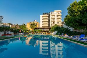 a large swimming pool with blue chairs and buildings at ALİBABAM APART OTEL in Kuşadası