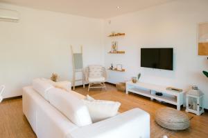 a living room with a white couch and a tv at Sea Spot Soltróia in Carvalhal