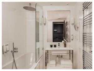 a white bathroom with a sink and a shower at Le Rayz Vendome in Paris