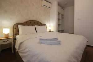 a bedroom with a white bed with two lamps and towels at Perla Sudului - Residence in Timişoara