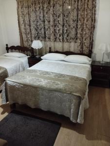 1 dormitorio con 2 camas y cortina en Apart & Hostal ManuAlé, en Tacna