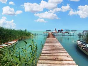 a wooden bridge over the water with two boats at TópART Apartman B Little House in Balatonfenyves