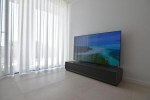 telewizor z płaskim ekranem siedzący na stojaku w pokoju z oknami w obiekcie LLUISALBERT w mieście L'Escala