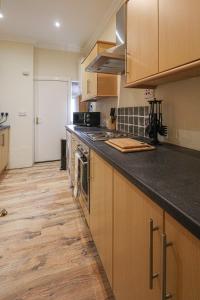 a kitchen with wooden cabinets and a counter top at Cosy Ardrossan Apartment in Ardrossan