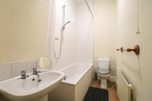 a bathroom with a sink and a tub and a toilet at Cosy Ardrossan Apartment in Ardrossan
