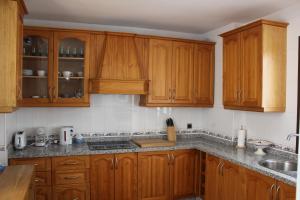 Una cocina con gabinetes de madera y un fregadero. en Casa Esmeralda by CasaTuristica, en Ronda