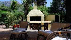 two chairs and a table with wine glasses in front of a fireplace at Villa Assunta in Tertenìa
