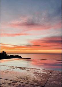 een zonsondergang boven een strand met de oceaan bij CapeStays - Villa Infinity in Kaapstad