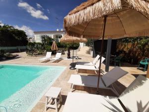 una piscina con sillas y sombrillas junto a una piscina en VILLA RASOA chambre LIBELLULE, en Cap d'Agde