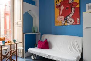 un soggiorno con divano bianco e un dipinto di una mucca di Mar y Arte Apartamentos a Málaga Altre 22 foto